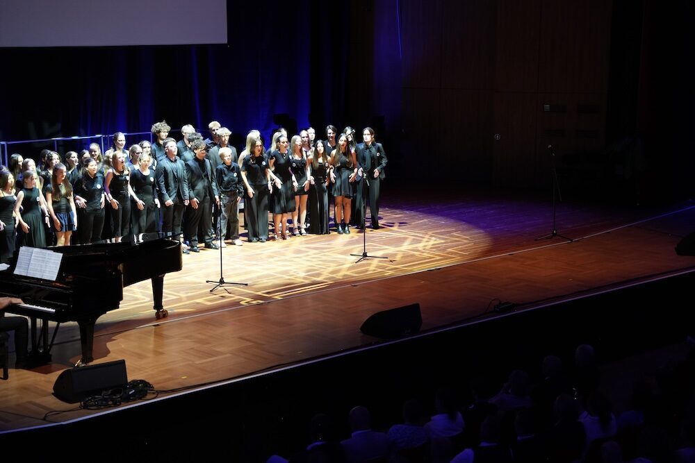 Großer Chor in Schwarz am Flügel auf der Bühne, Best of Schulwerk 2026