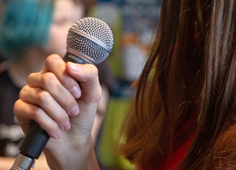 Schülerin hält ein Mikrofon bei der Popband der Maria-Ward-Realschule Neuburg