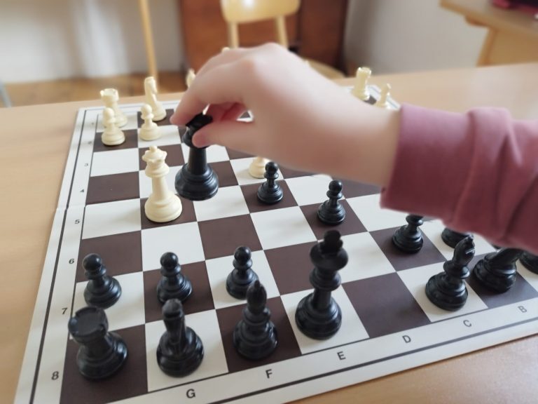 Hand setzt eine schwarze Schachfigur, Schach-AG der Maria-Ward-Realschule Neuburg