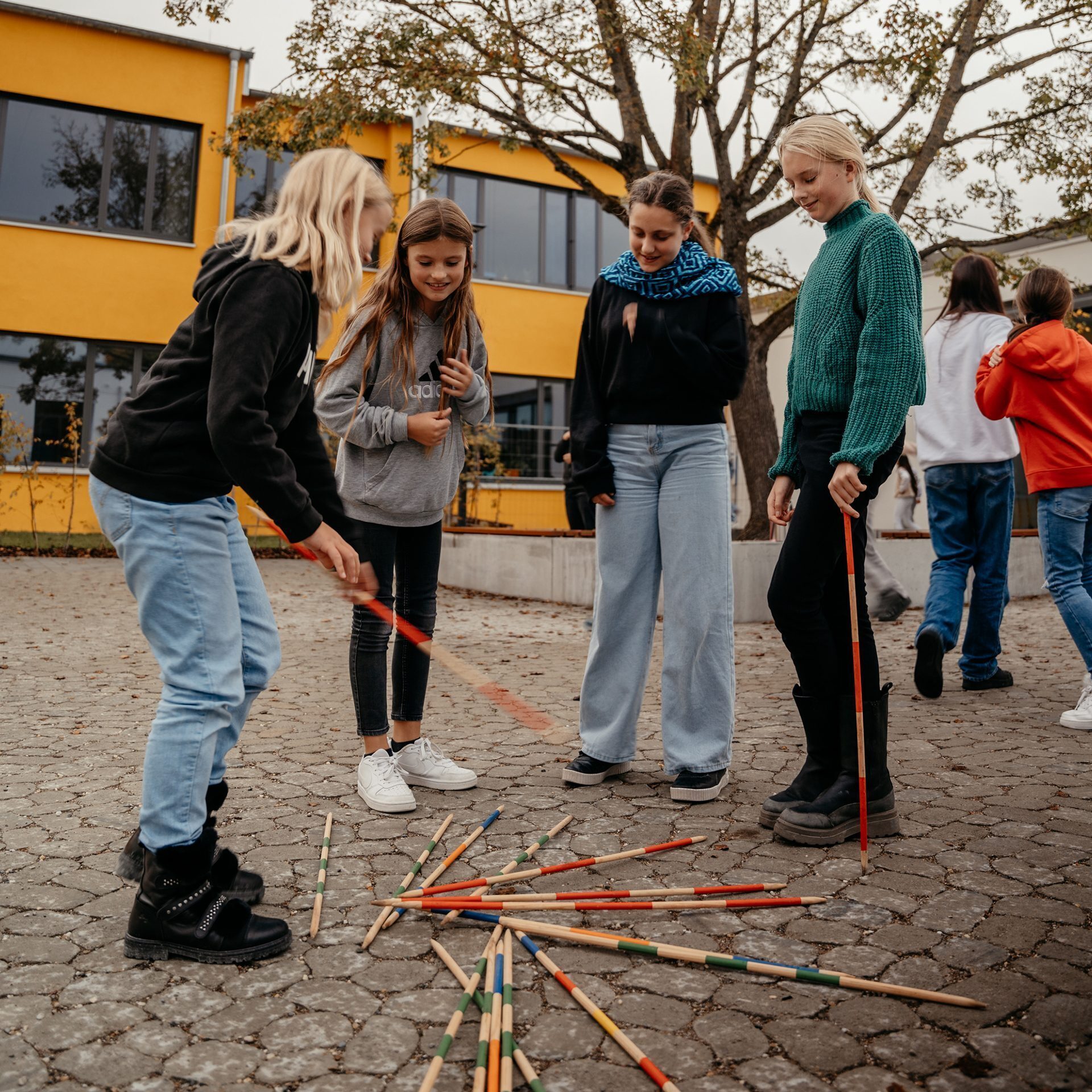 Schülerinnen spielen auf dem Schulhof Riesenmikado
